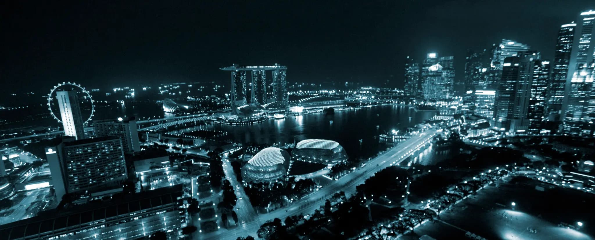 A city's business district at night, towers lit along the water.