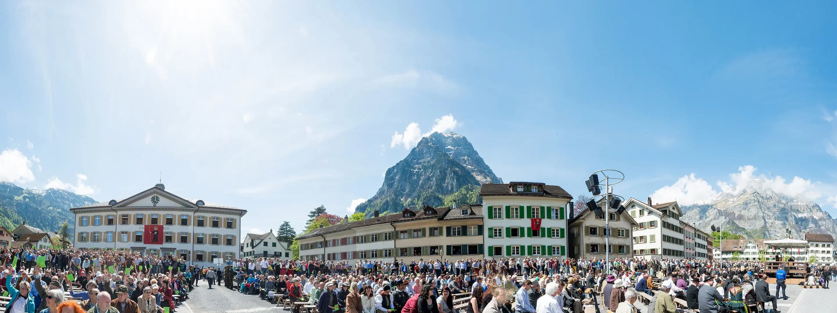 La Landsgemeinde de Glaris : des milliers de citoyennes et citoyens réunis sur la place sous les Alpes, décidant de leurs lois à ciel ouvert.